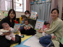 小さな赤ちゃんを抱っこして座った母親が、完成した作品を持っている写真