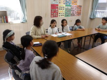 ロの字に並んだ長机に女性職員と子供たちが座り、2024年度最初のこども運営会議の顔合わせが行われている様子の写真