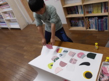 着れなくなった衣類を切って白い鯉のぼりの鱗を作る男子児童の写真