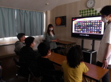 学習室に設置されたゲームの映像が映し出された大型テレビでゲームをする子ども達の写真