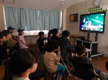 小学生と中学生が一緒にテレビゲームで遊んでいる様子の写真