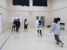 集会室で女の子たちが大繩飛びに挑戦している様子の写真
