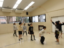 集会室で8の字になって大繩を潜り抜ける子供たちの写真