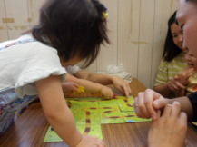 長机の上に置かれたボードゲームを楽しむ女の子と父親の親子の写真