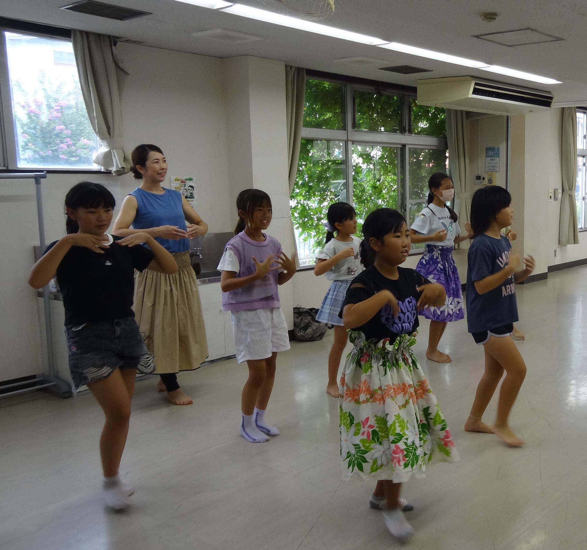 小学生がフラの振りをつけて踊る様子