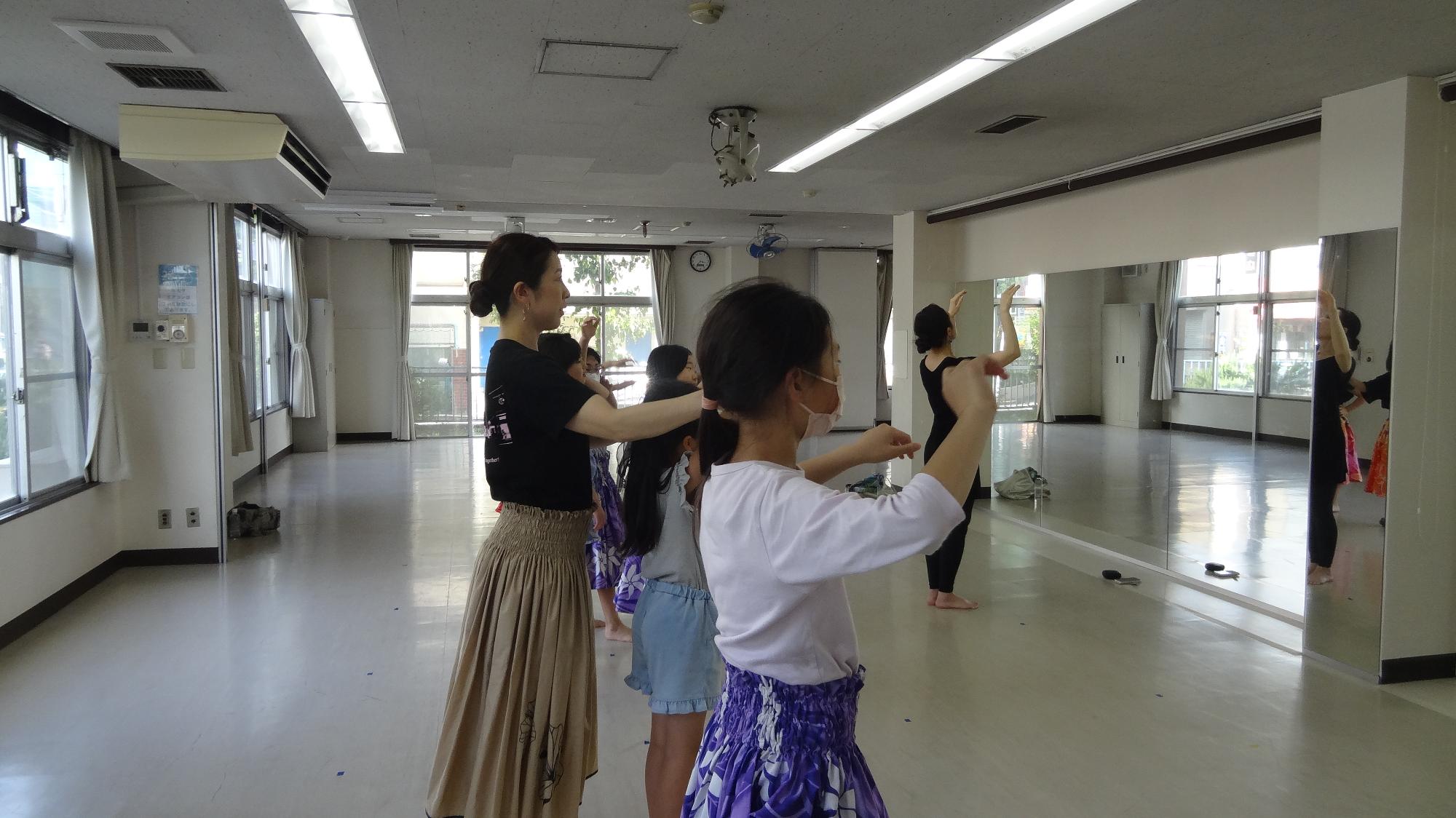 子どもたちが講師と一緒に踊りの振りを確認している様子