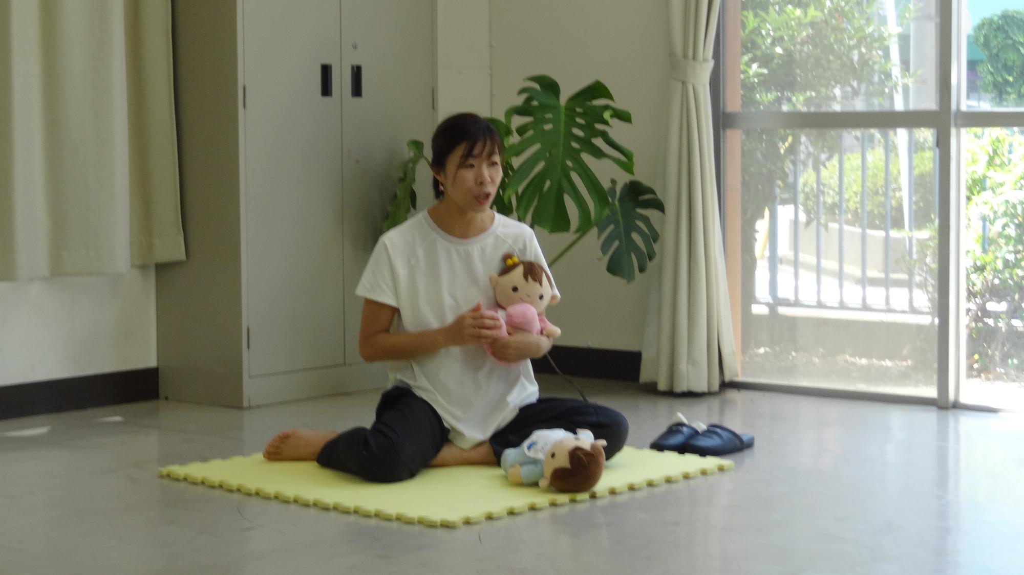 赤ちゃん人形を使用してマッサージの説明をする講師