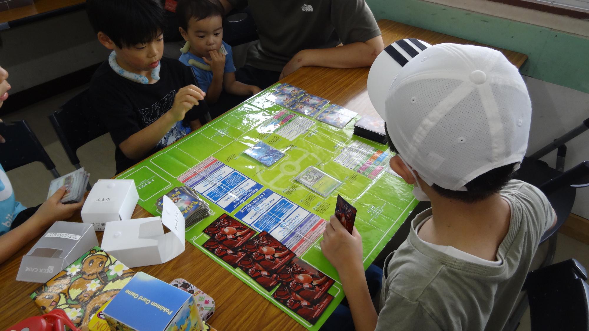 子どもがポケモンカードを使用して相手と対戦する様子