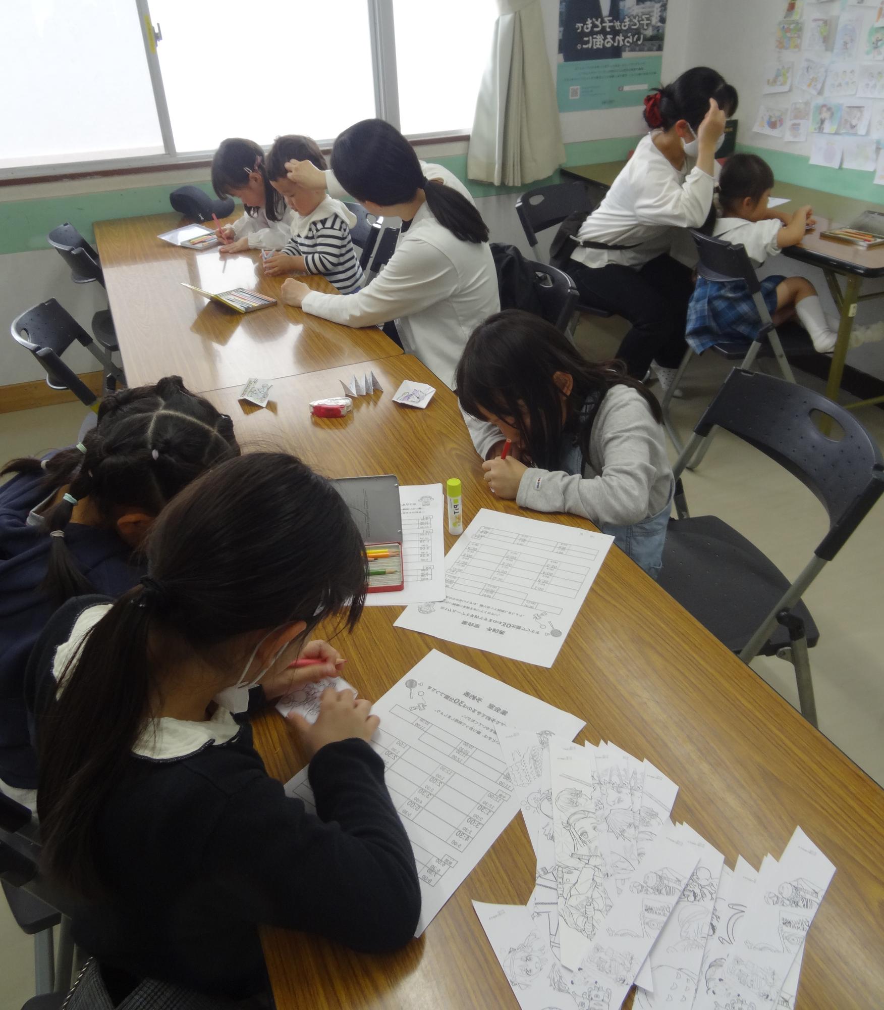 工作をする小学生と幼児親子の写真