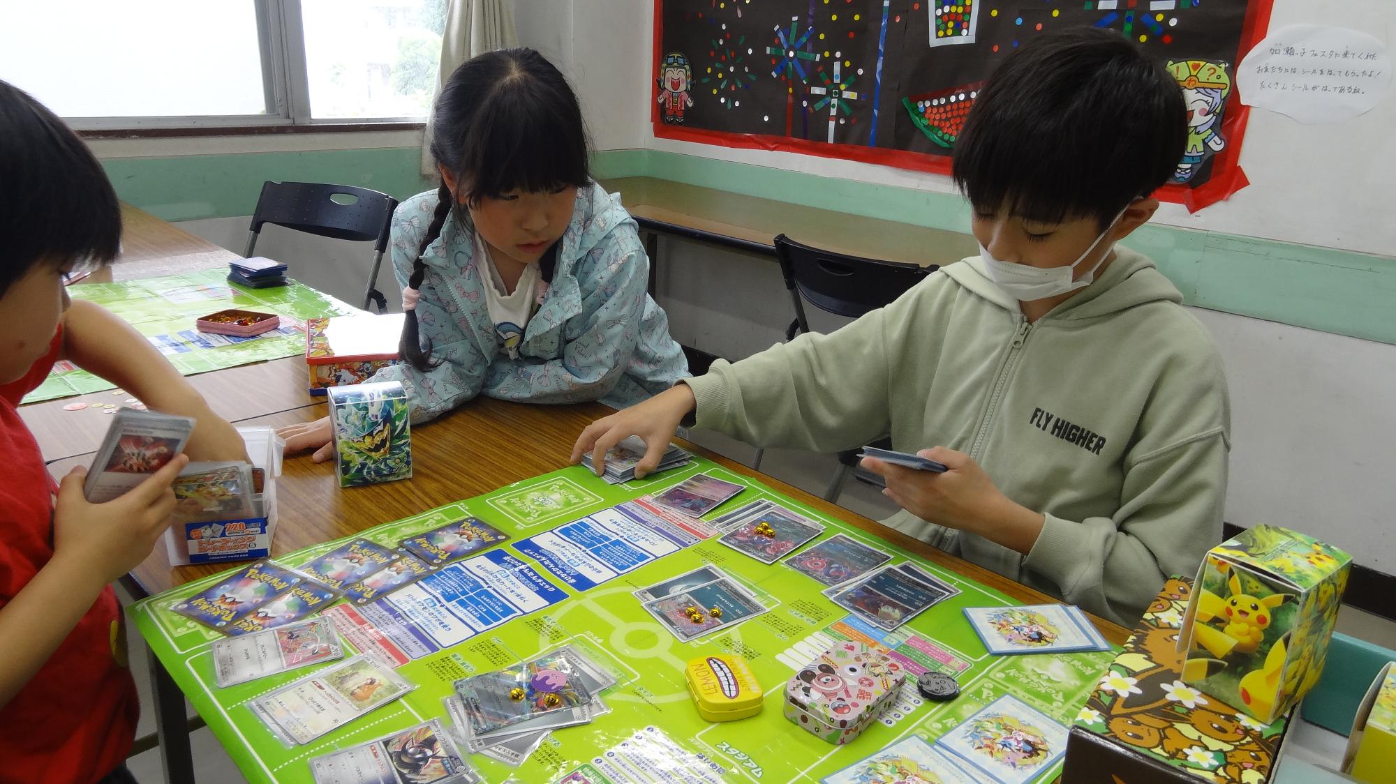 子ども同士がポケモンカードで対戦している様子