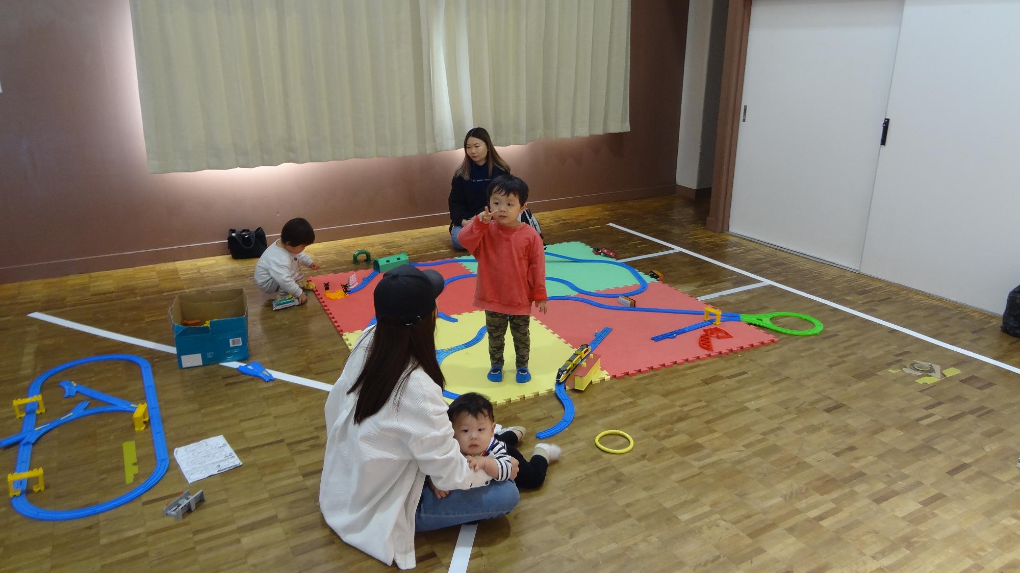こぶんの集会室にてプラレールでこどもたちとその保護者が遊んでいる様子の画像