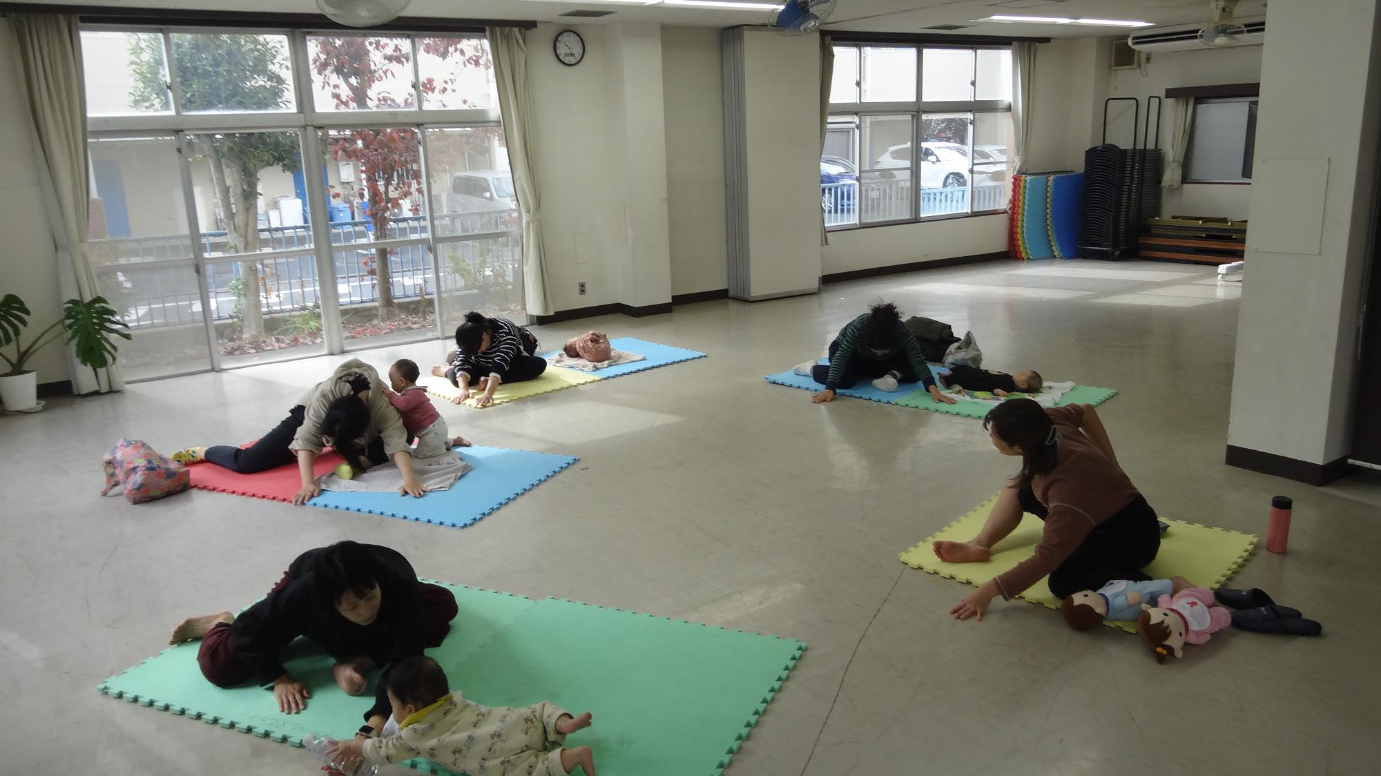 4組の幼児の保護者が一番右の先生の真似をしながら、前屈姿勢をしている様子