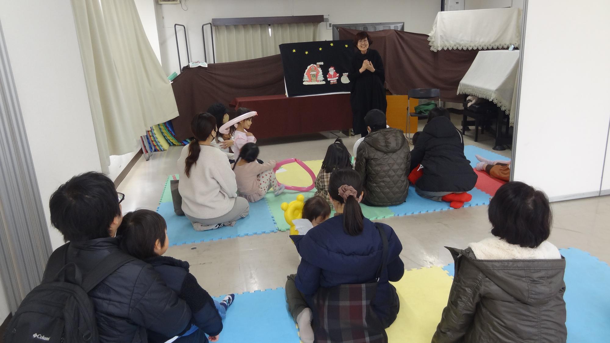 おはなし会の先生がお話をしている様子。多くの幼児親子がそれを見ている様子