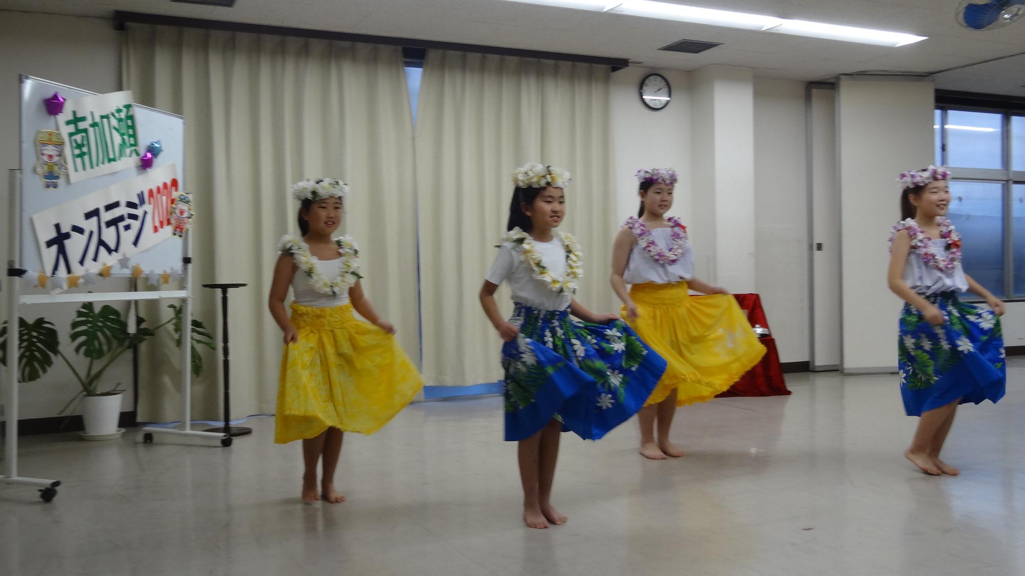 4人の児童が横に並んでフラダンスをしている様子