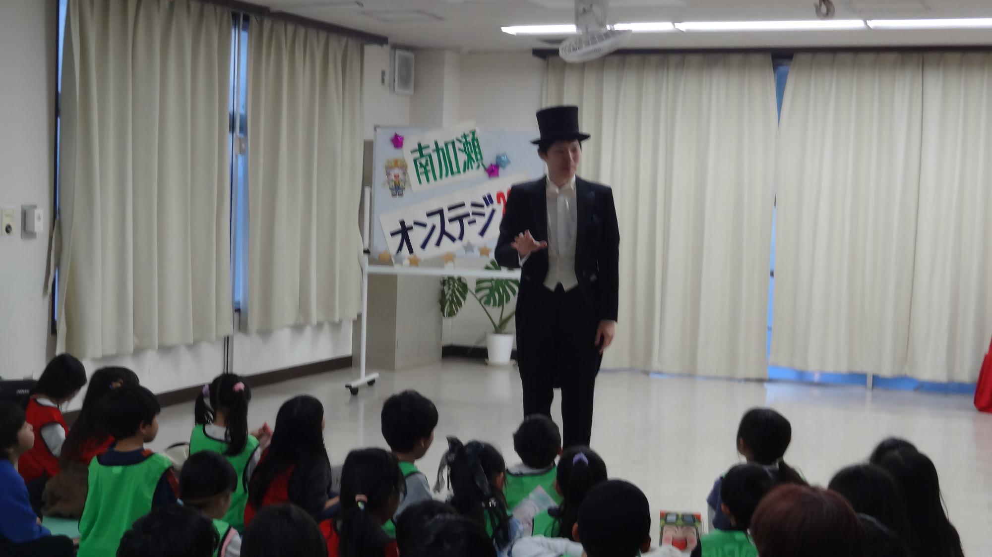 マジシャンがこどもたちの前でお話している様子