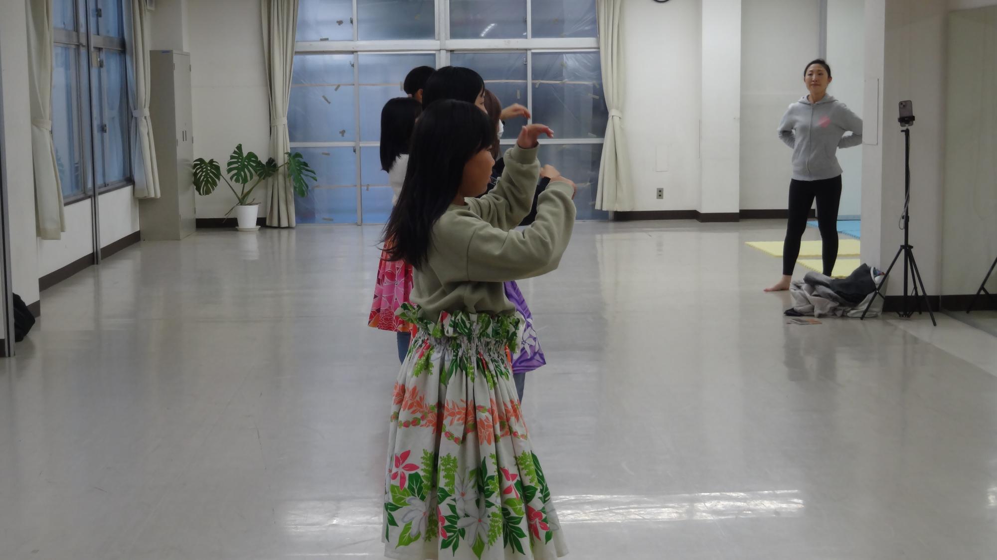 フラダンスの練習をしている様子。それを先生が見ている様子。