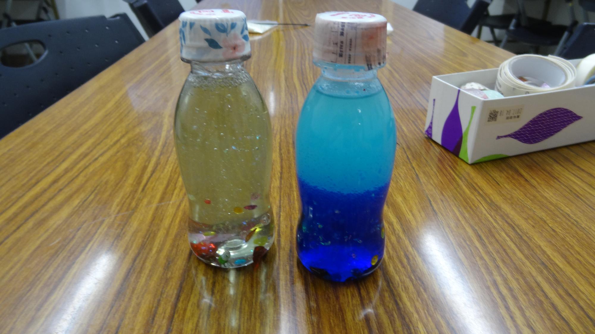 ペットボトルにキラキラのラメを入れて、その中に洗濯のりと水を入れたもの（左）。ペットボトルにキラキラのラメを入れて、その中に油と水を入れたもの（右）