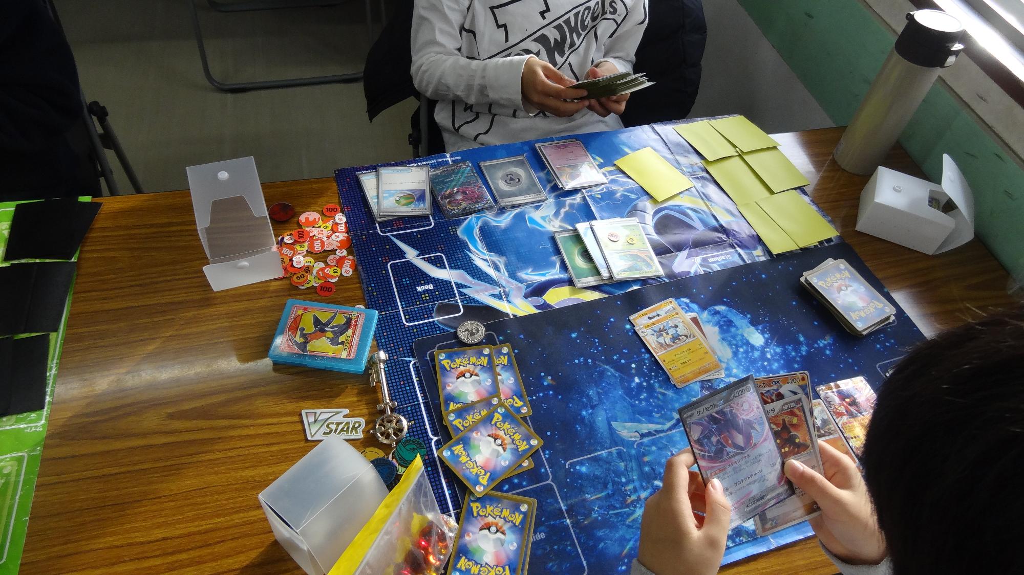 ポケモンカードバトルをしている小学生がポケモンカードを眺めている様子。