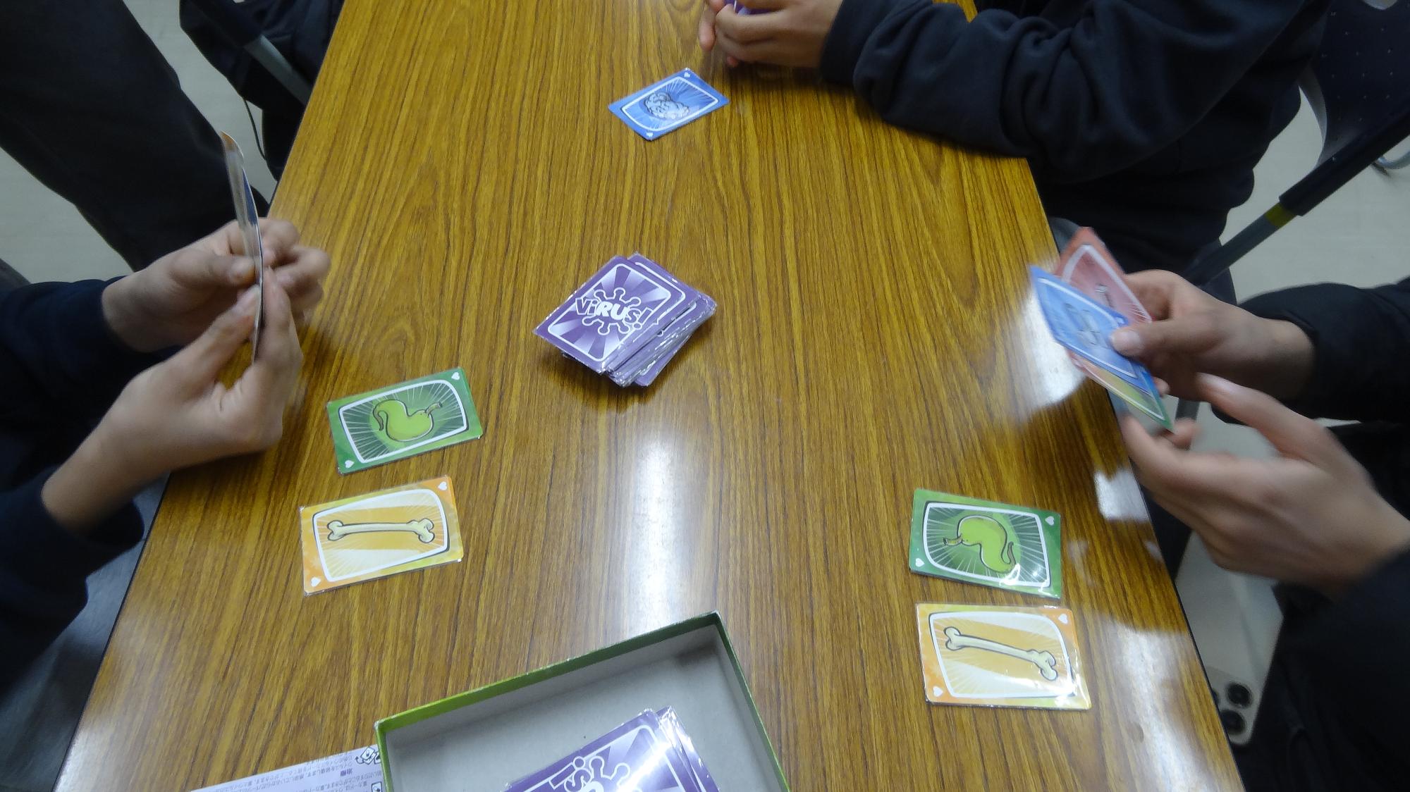 カードを持っているよう児童が3人で対戦している様子