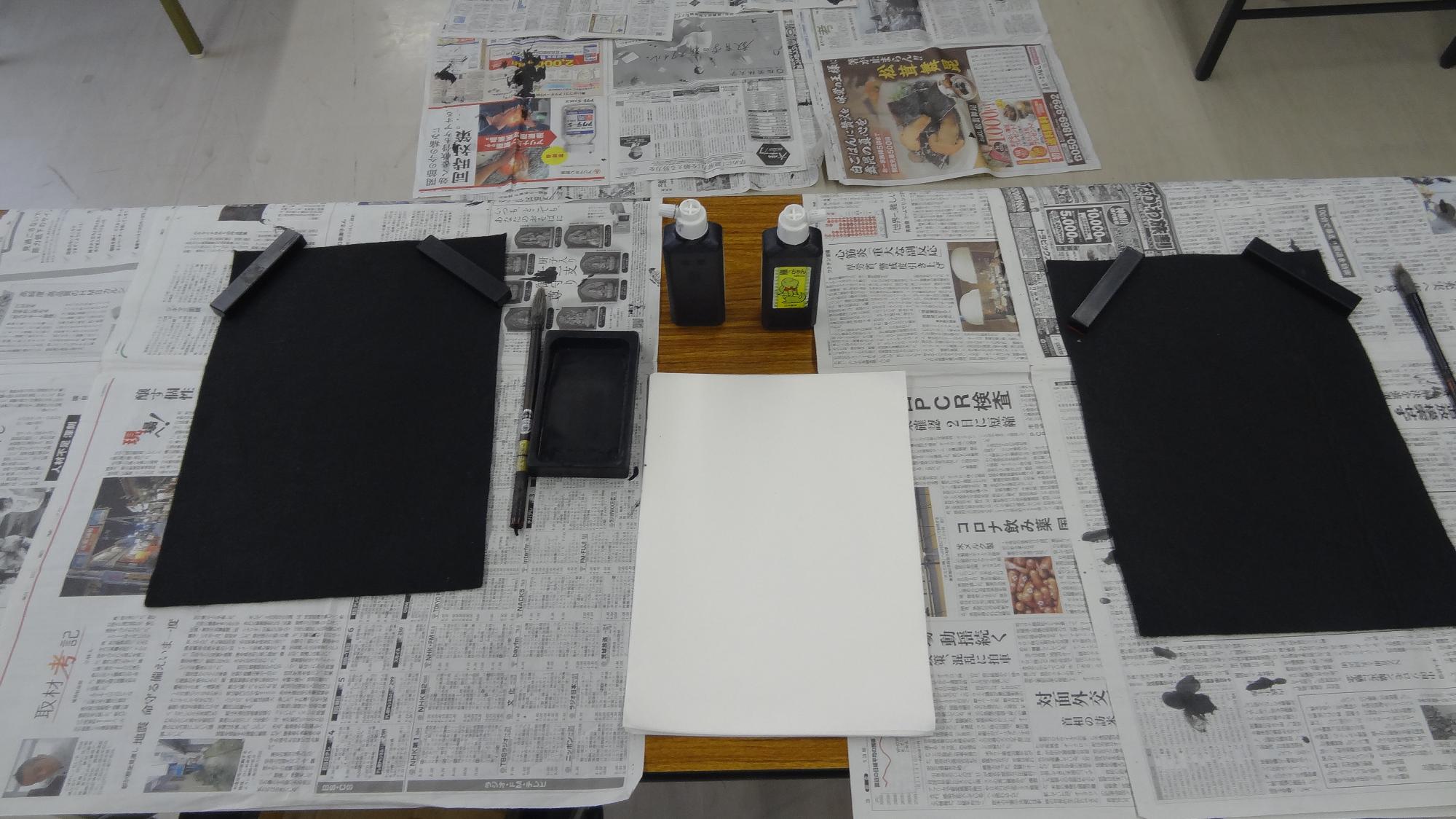 左右に黒い下敷きが置かれていて、真ん中に半紙が置かれている様子