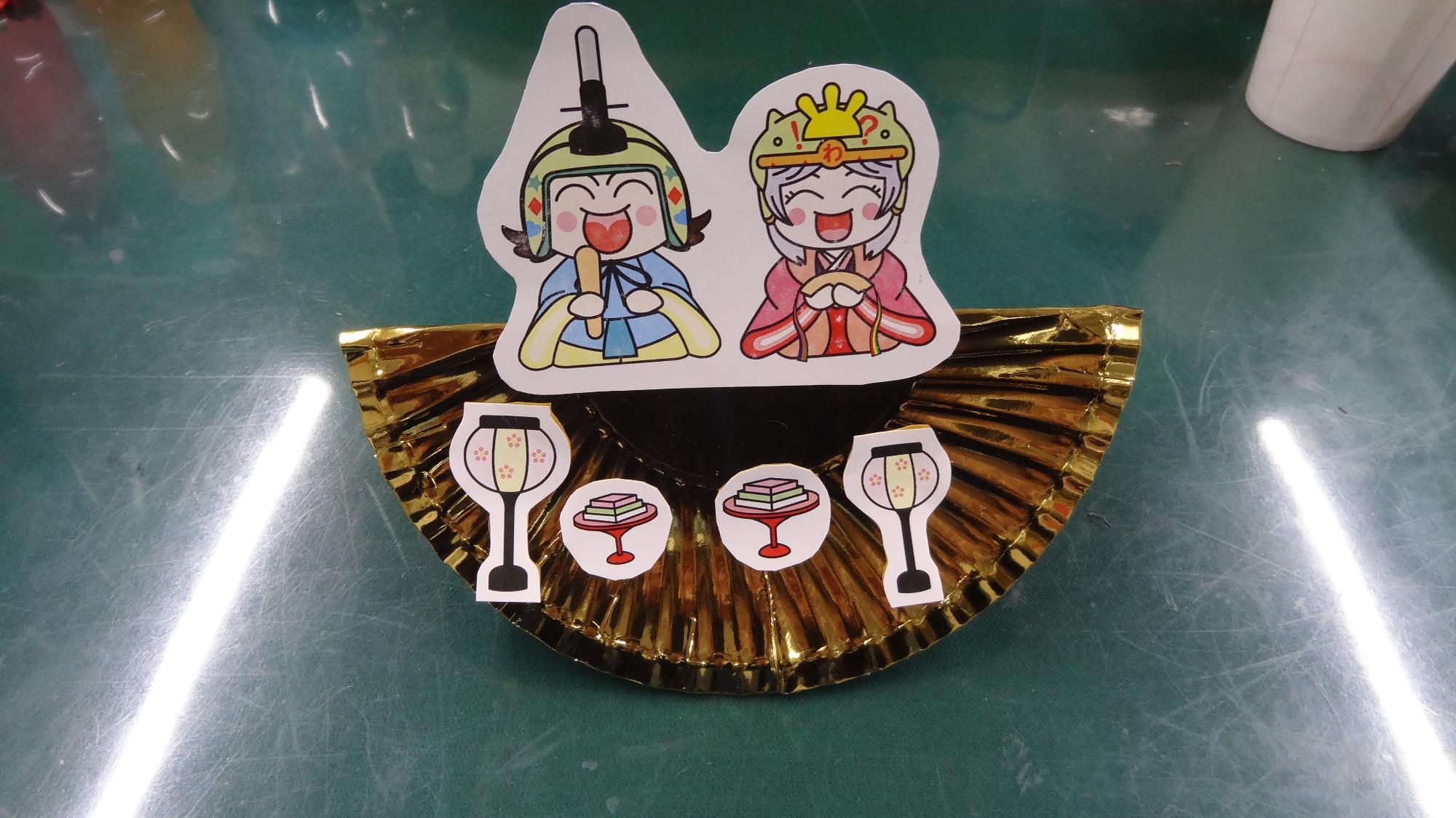 こぶんたとわくりんのひな祭りデザインを金色の紙皿に貼った作品
