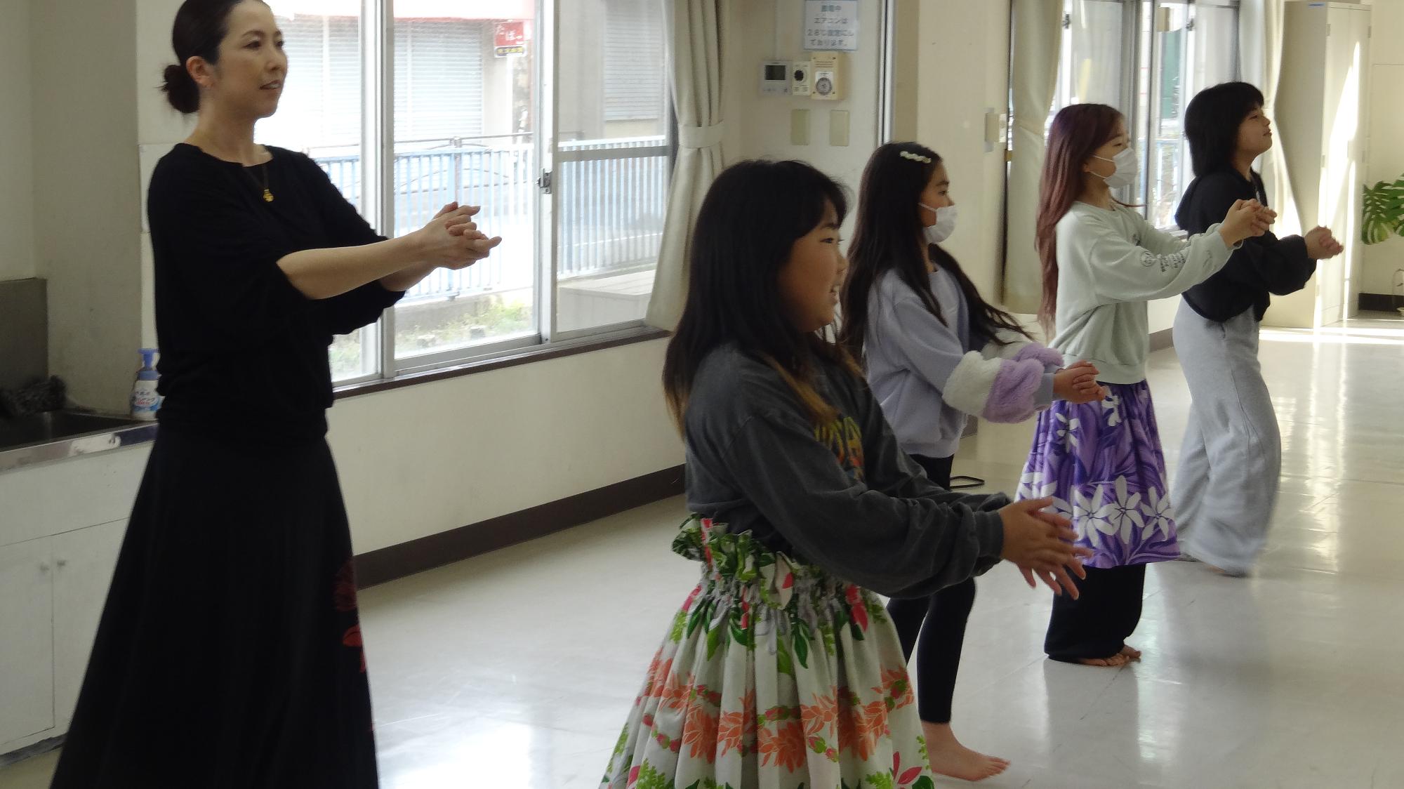 小学生4人がフラダンスをしている様子。