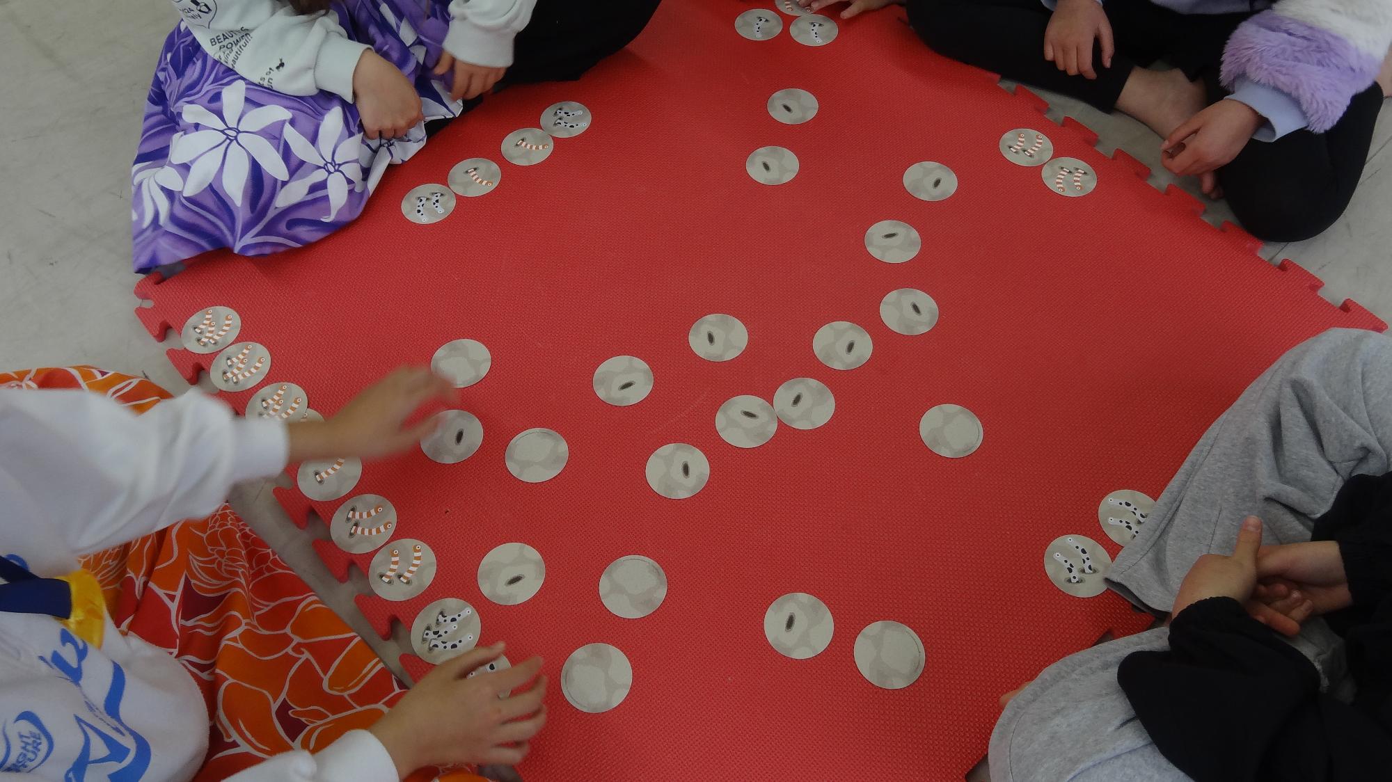 赤いマットの上で輪になってちんけいすいじゃくをしている様子