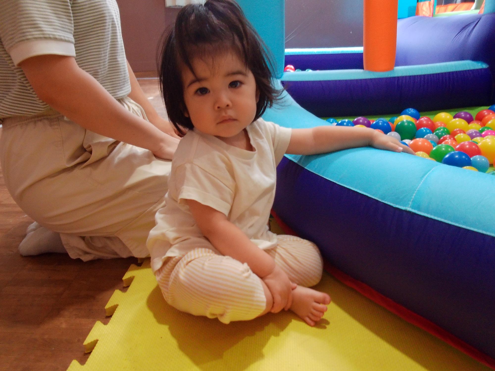 幼児がボールプールのそばで座っている様子