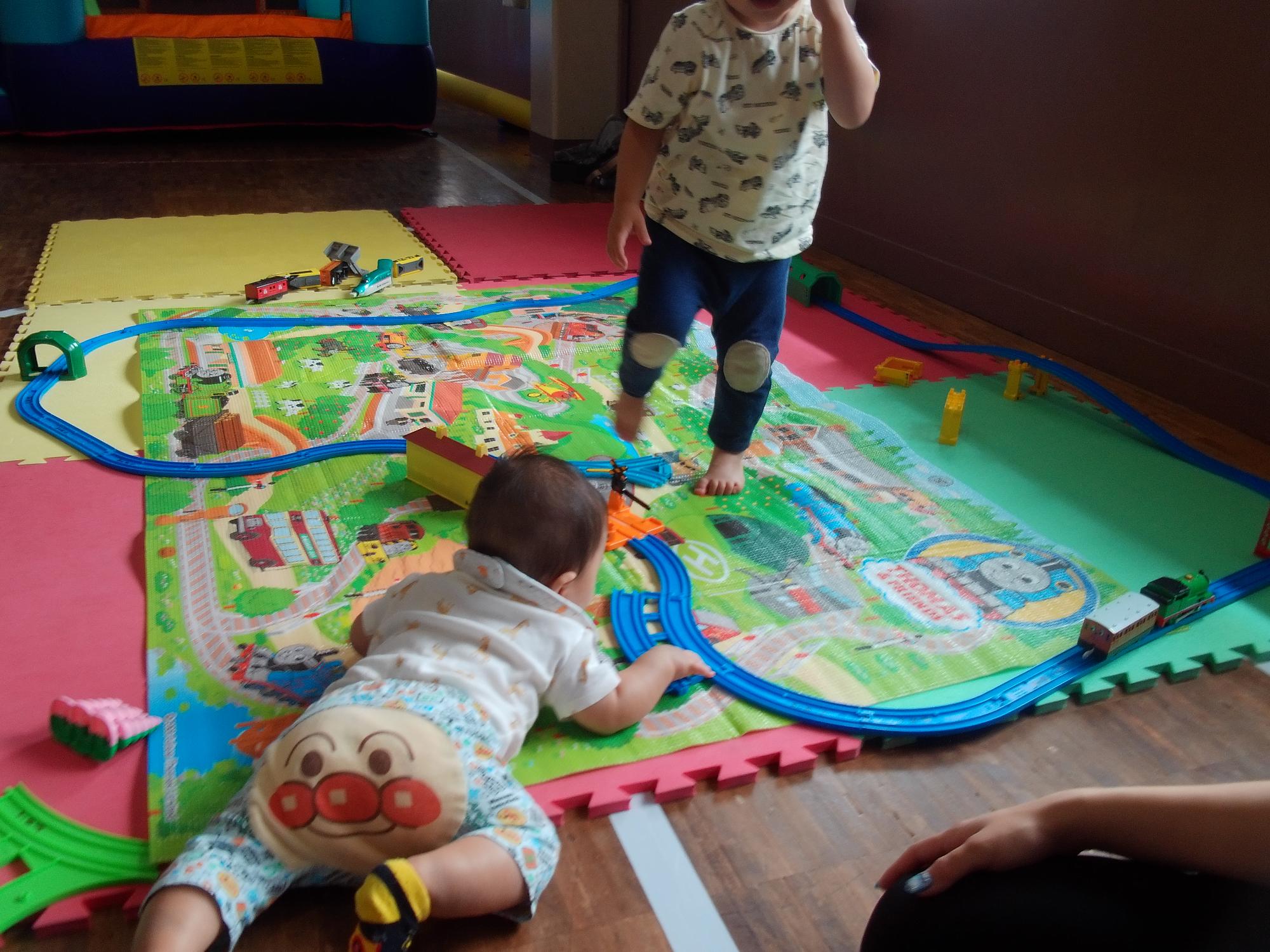 乳幼児がプラレールで遊んでいる様子