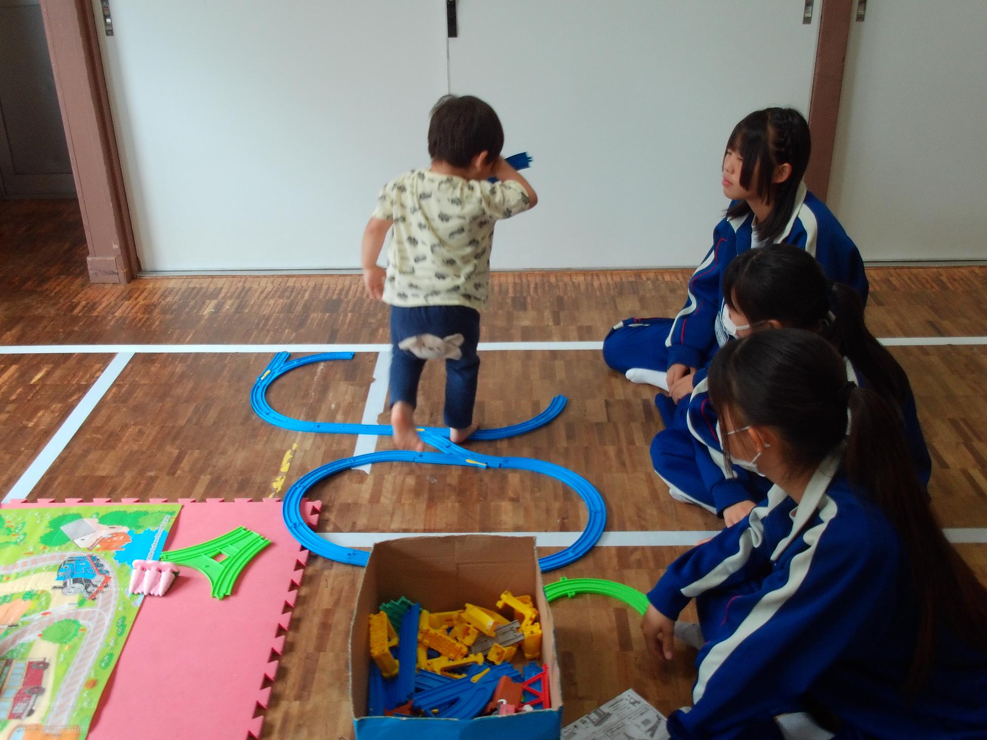 幼児が中学生と遊んでいる様子