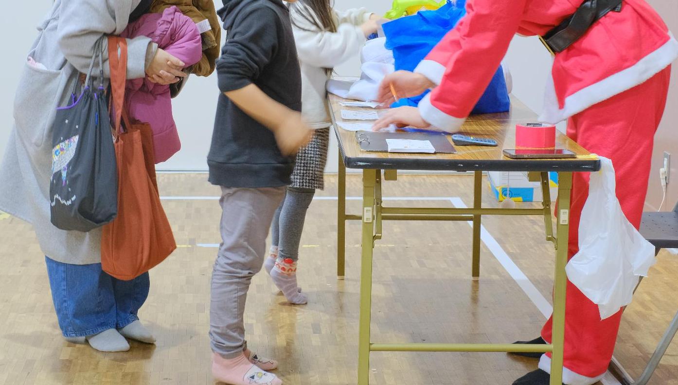 左側に親子、右側にサンタさんがいて、サンタさんが受付をしている様子