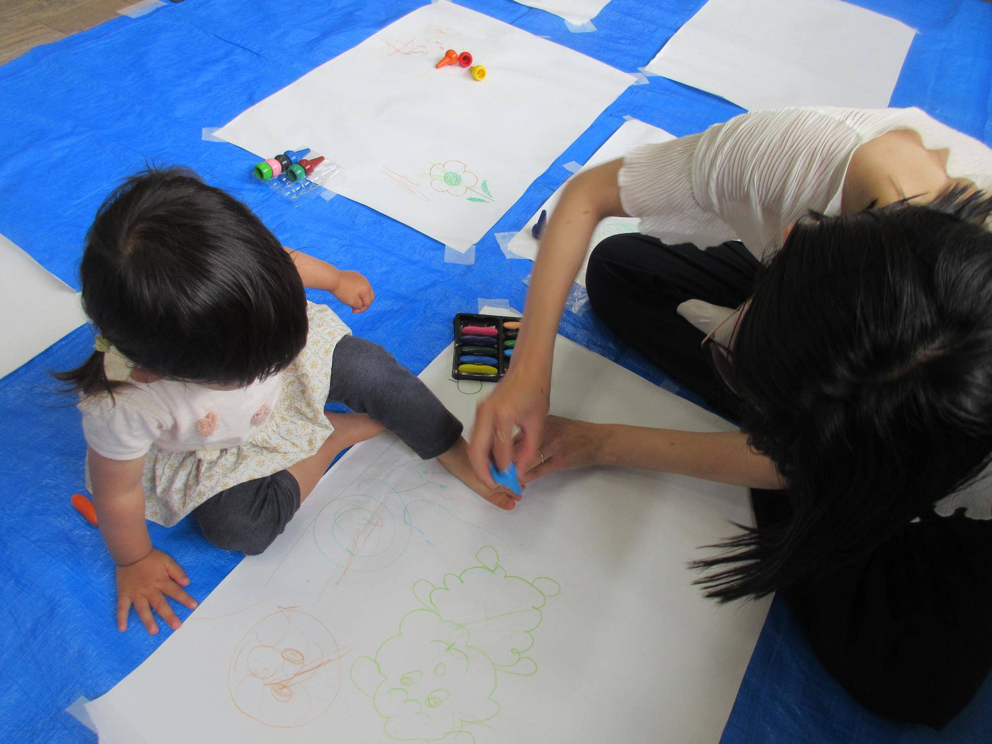 ぽぽんたらんどの行事で大きな紙に絵を書いて遊んでいる様子