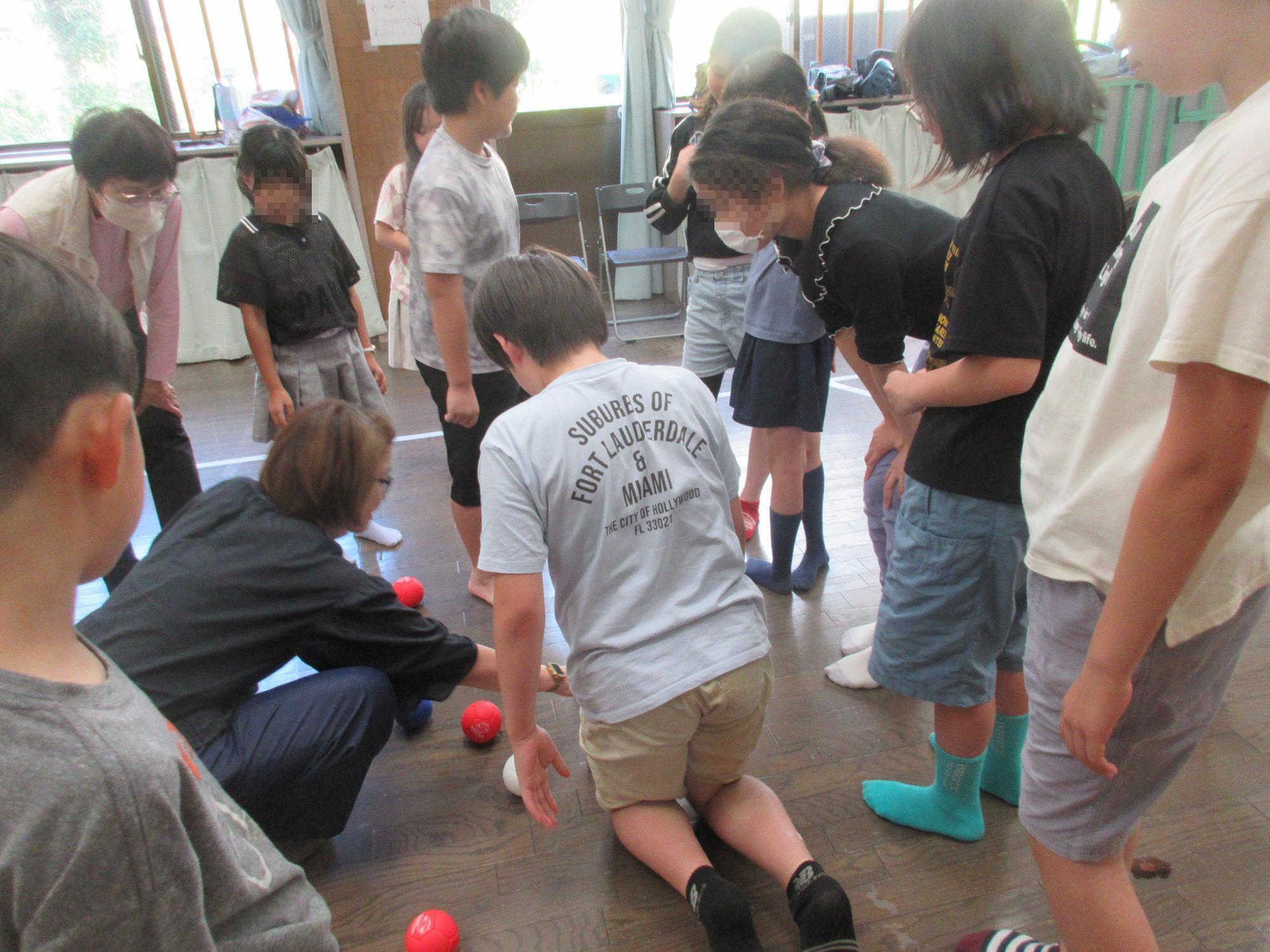 地域の方に教わりながら小学生がボッチャをしている様子