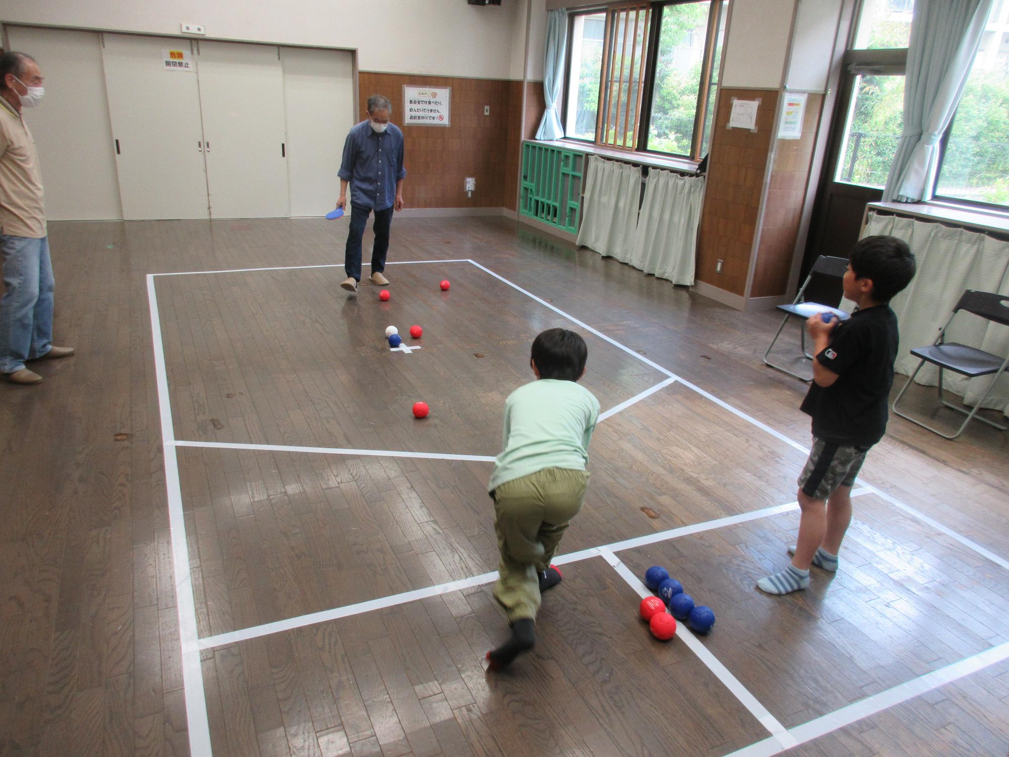 地域の方に教わりながら小学生がボッチャをしている様子
