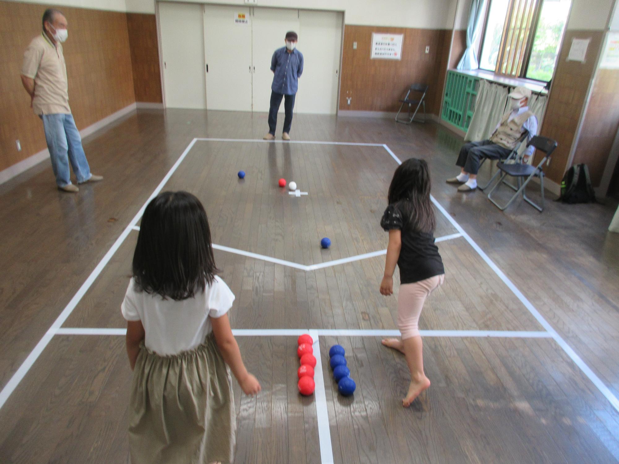 地域の方に教わりながら小学生がボッチャをしている様子