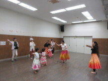 色鮮やかなフラダンスの衣装を着た講師と子供たちが踊っている写真
