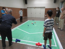 青いボールを投げる大人と対戦相手の男の子の後ろ姿を撮った写真