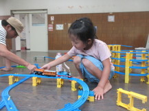 作ったコースに電車を乗せて走らせようとしている女の子の写真