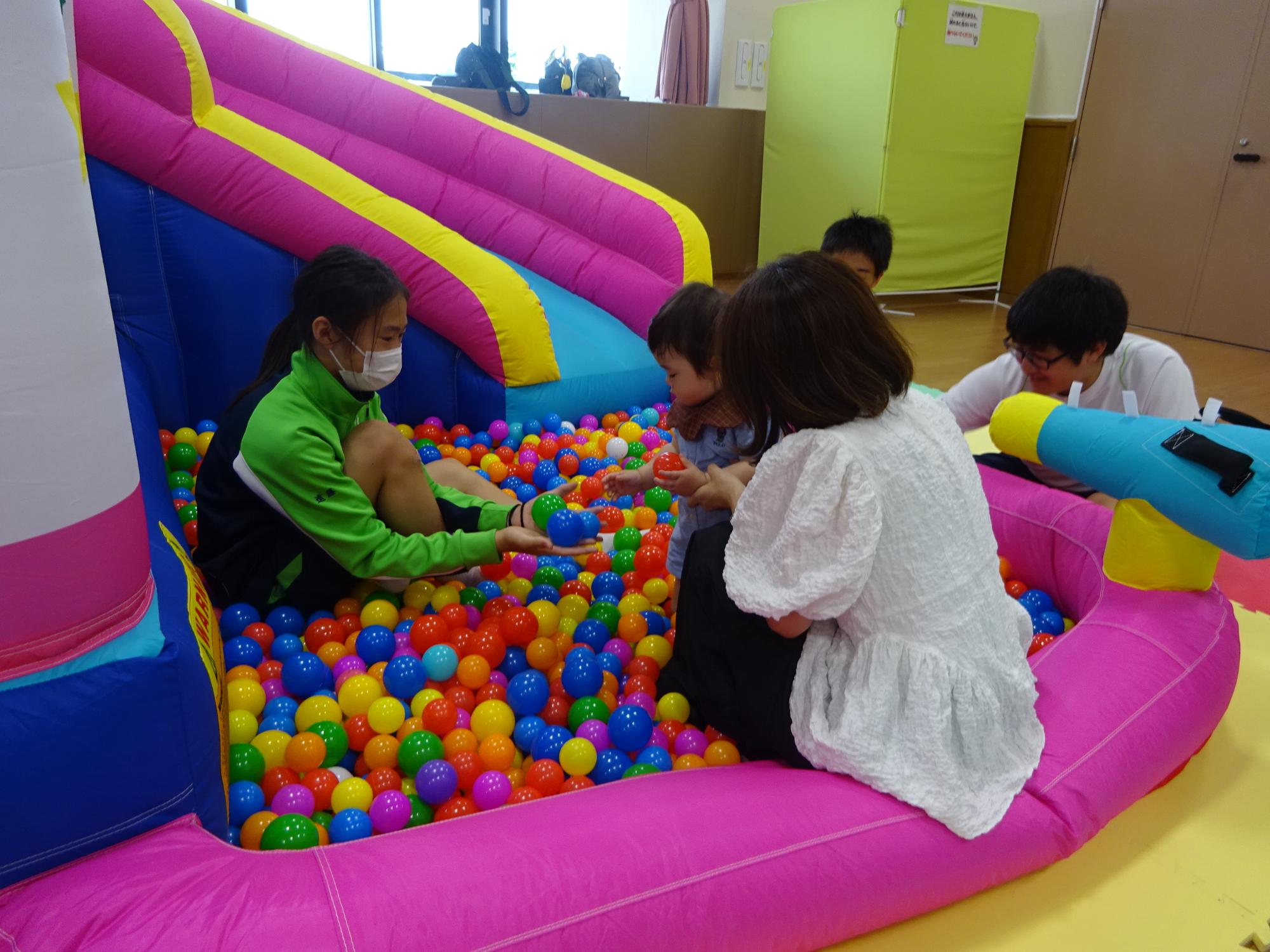 大型遊具のボールプールで遊んでいる乳幼児親子の写真