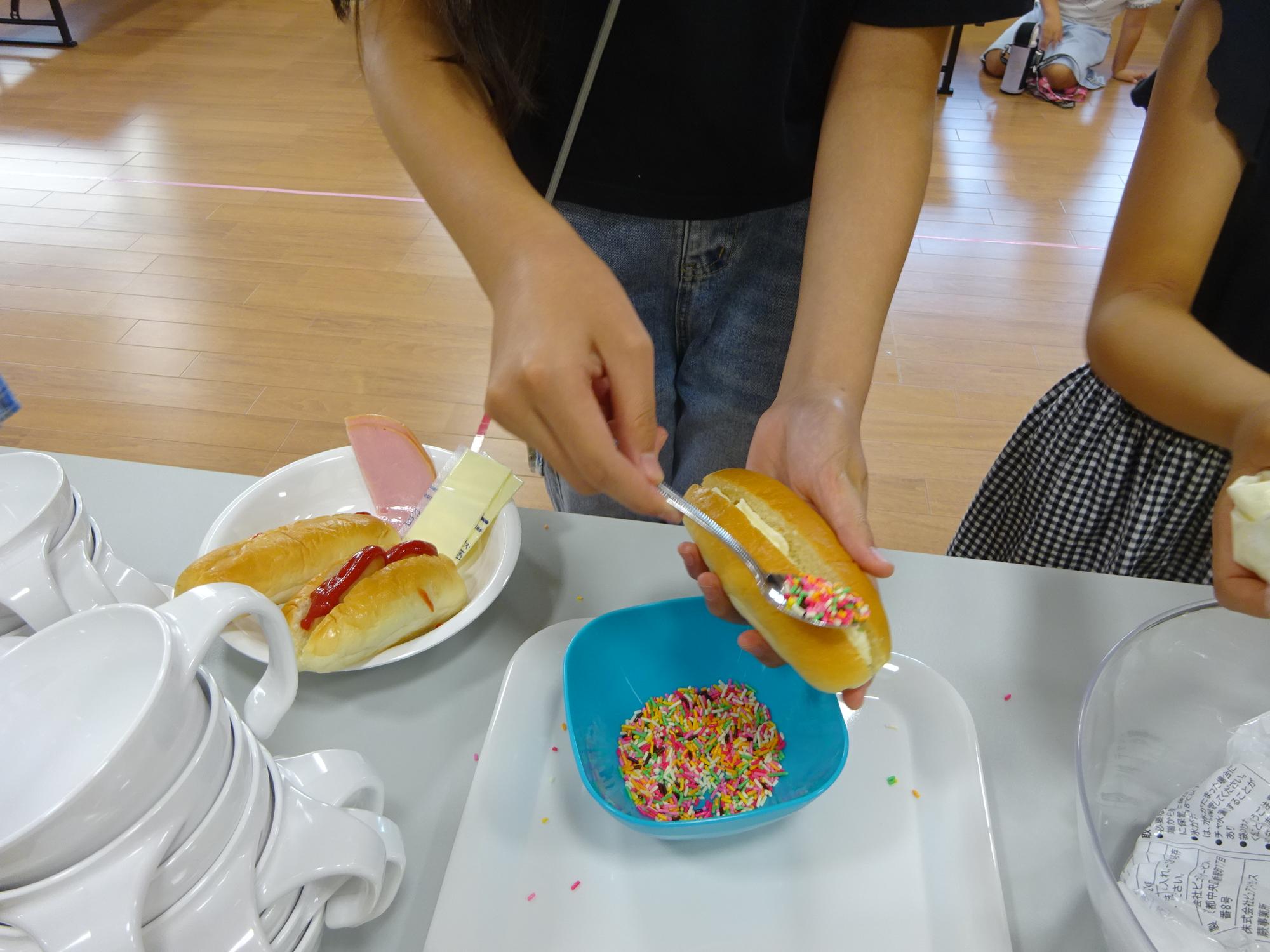 生クリームをはさんでカラースプレーで仕上げをしている子どもの写真