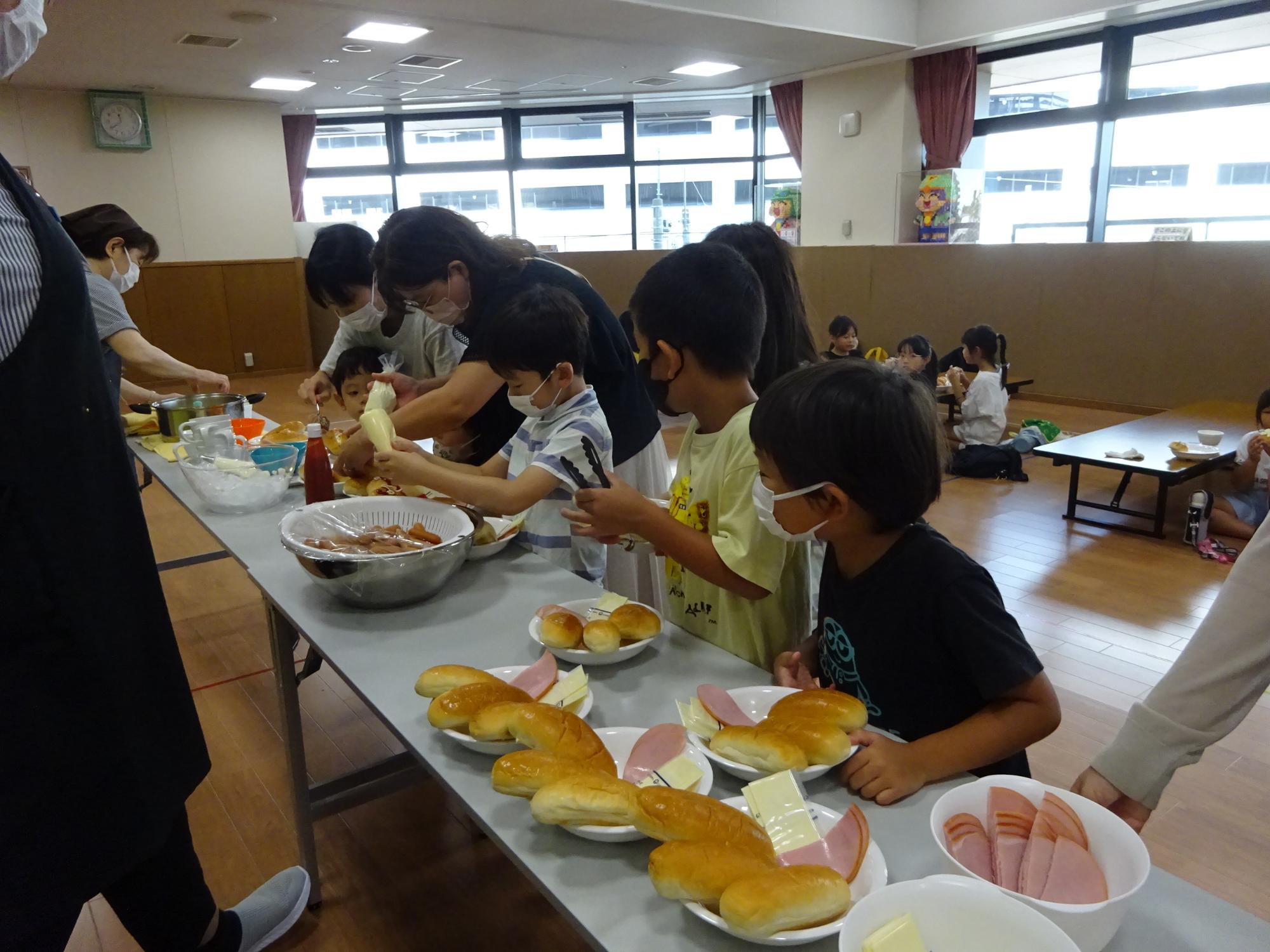 自分で具材をはさんでサンドを完成させている子どもたちの写真