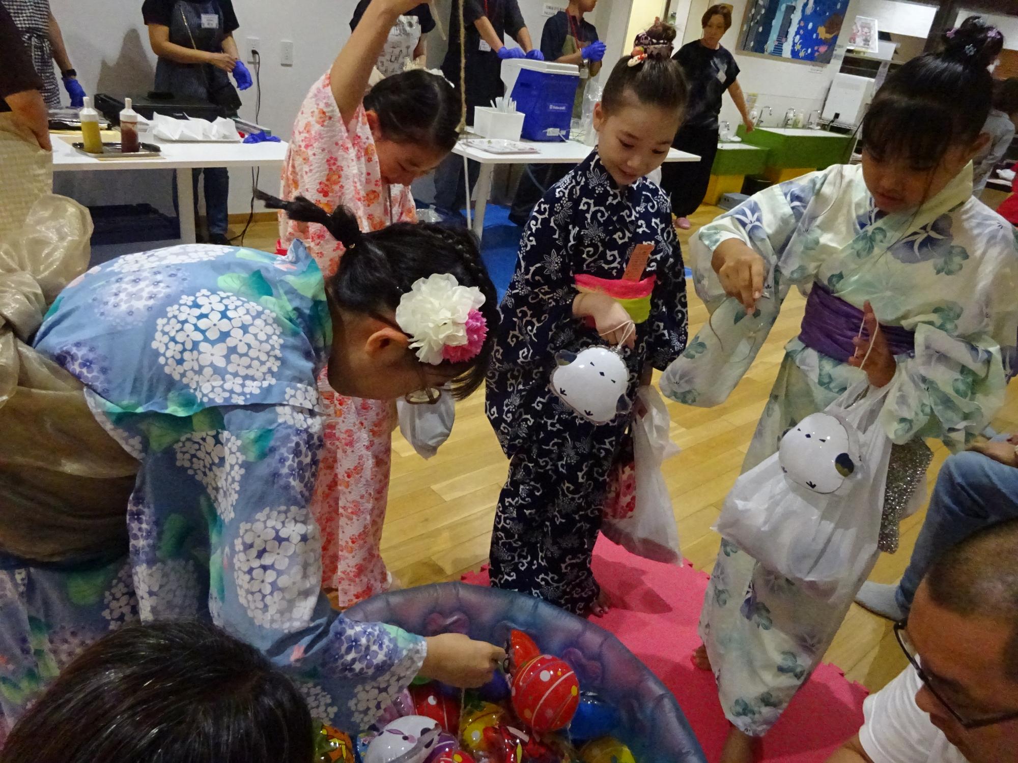 ヨーヨー釣りをしている浴衣の子どもたちの写真