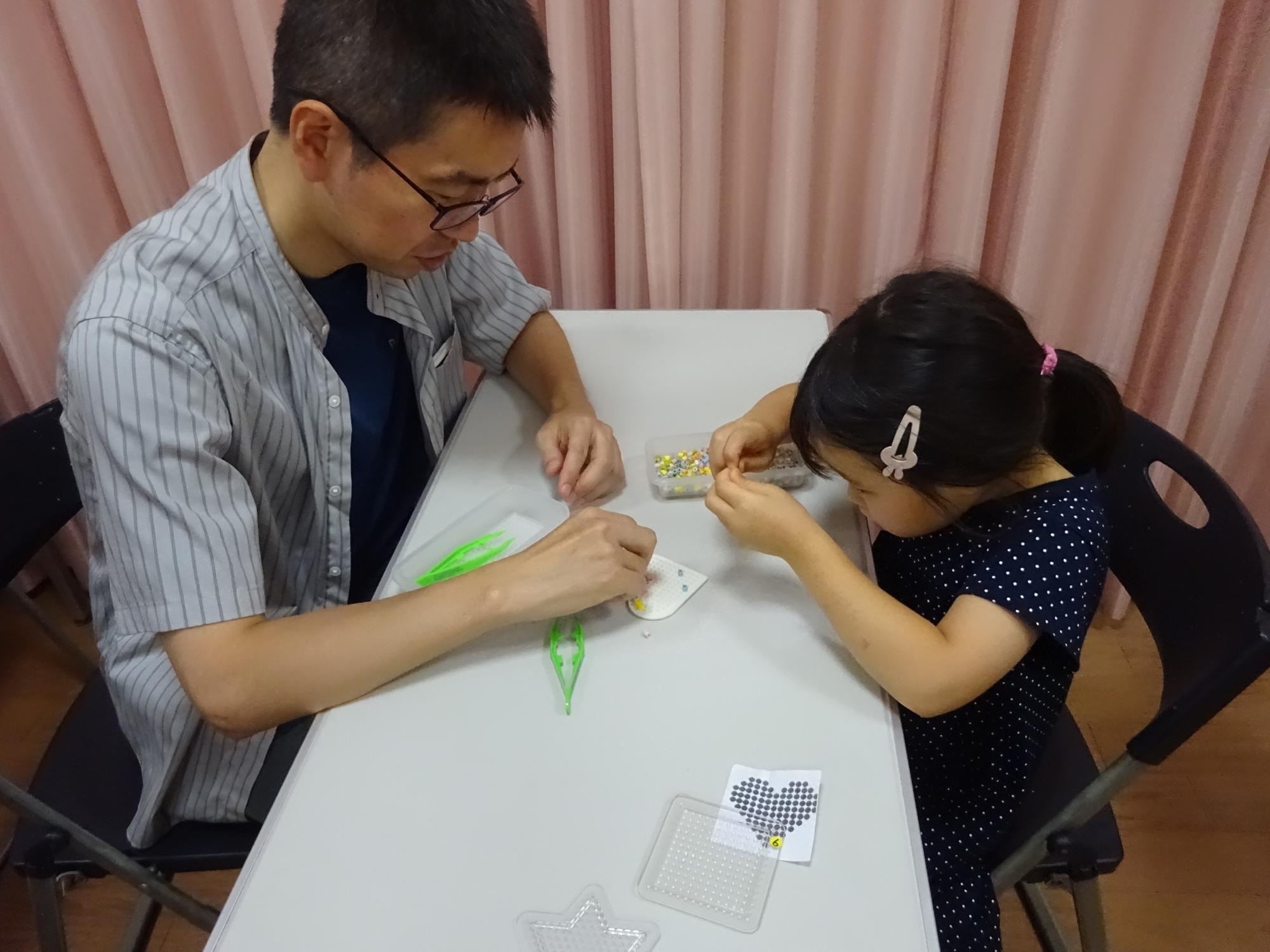 幼児親子がアイロンビーズを作っている様子の写真