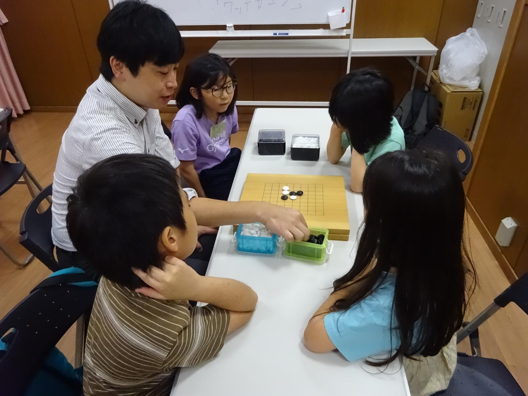 碁盤を使った囲碁の説明を聞いている子どもたちの写真