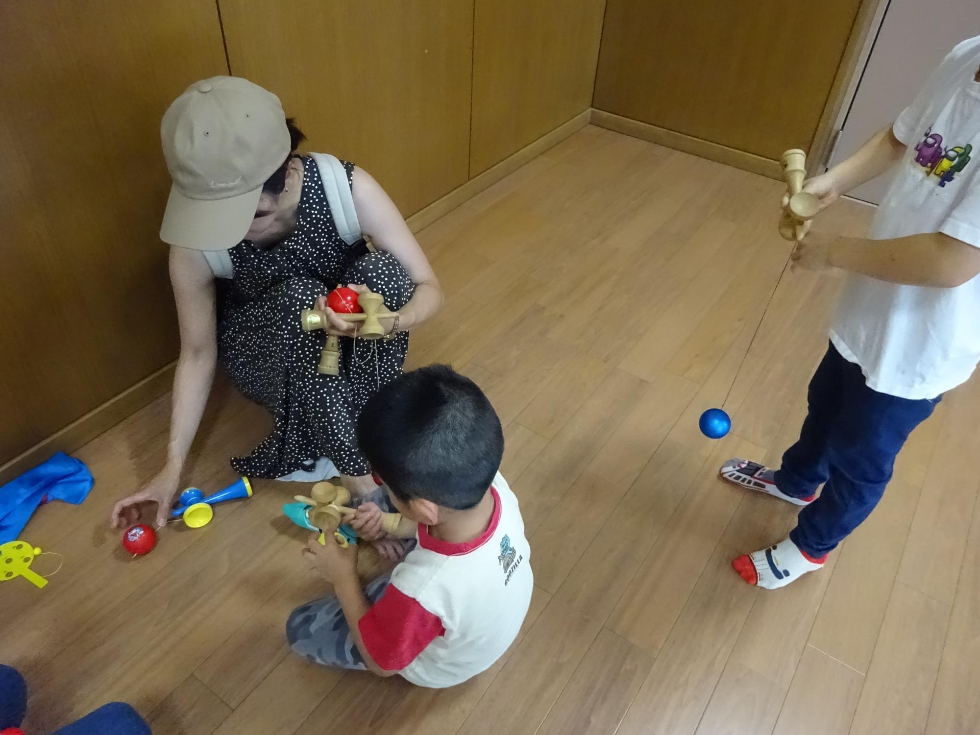 ユニークなけん玉で遊ぶ幼児親子の写真