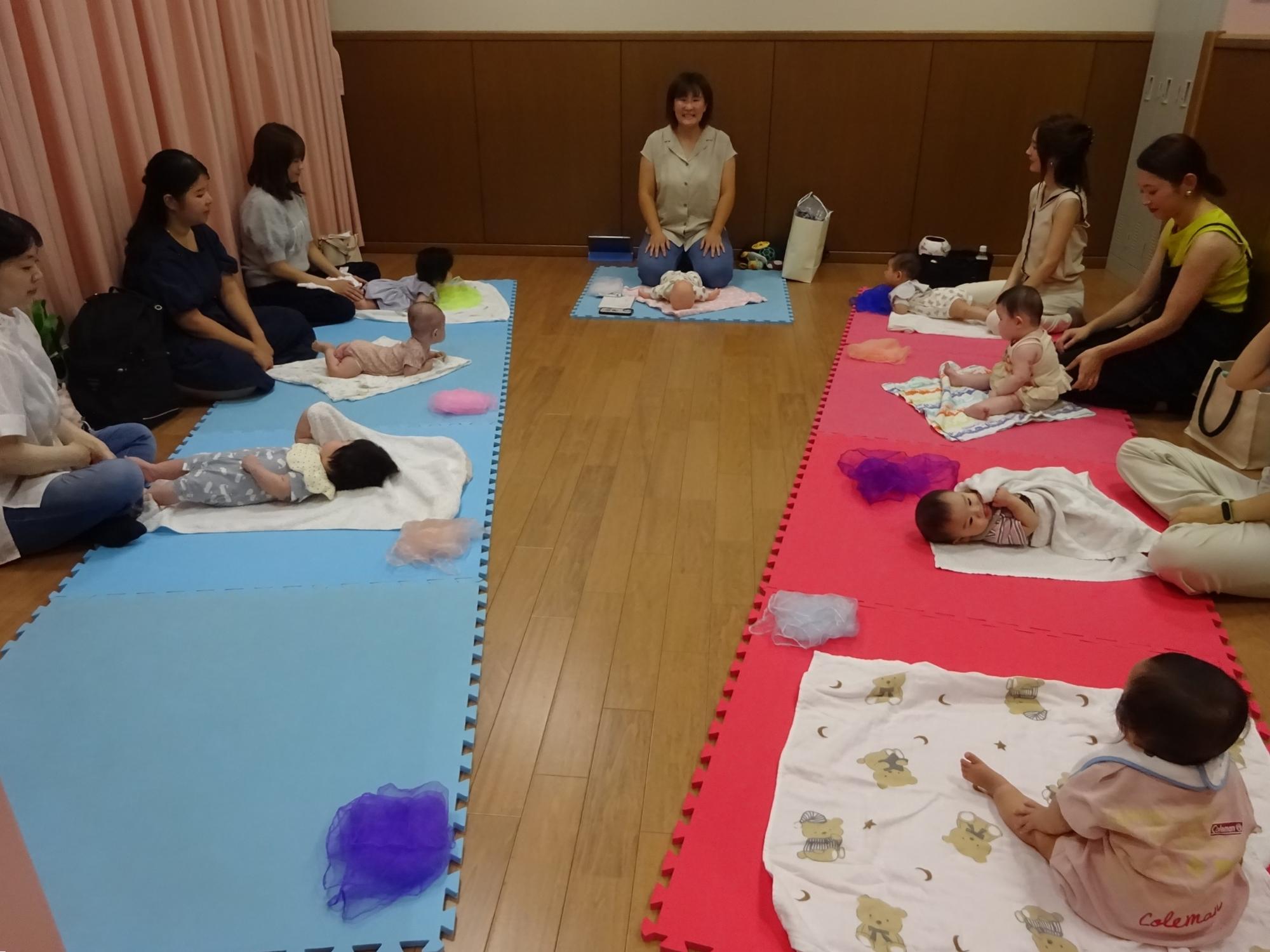 マットの上でベビーマッサージをしている様子の写真1
