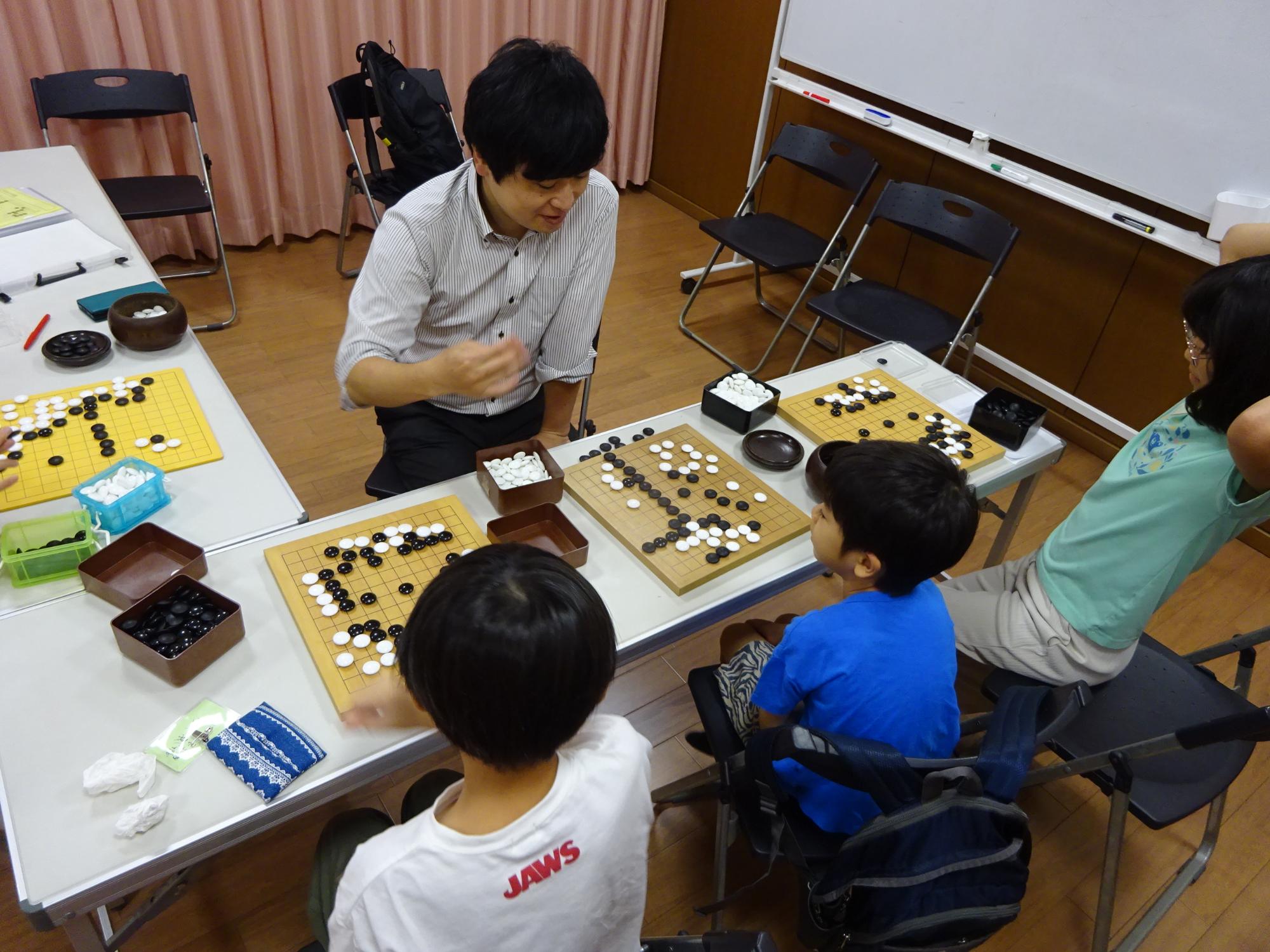 講師と対局をしている3人の小学生の写真