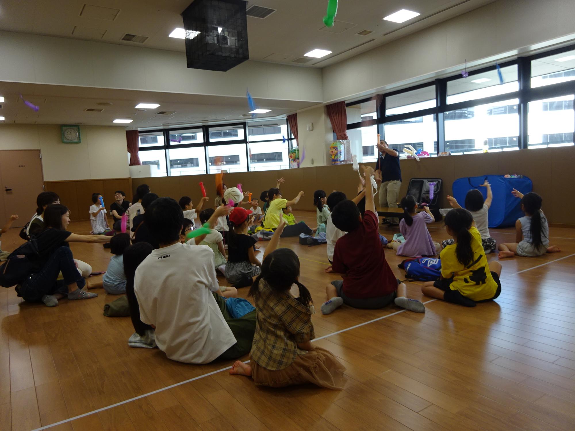 自分で作ったネズミのバルーンアートを飛ばす大勢の子どもたちの写真