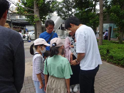 小杉こども文化センターの周辺を散策しながら講師の説明を聞いている参加者達の写真