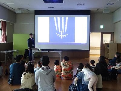 飛行機の写真を見ながら機長さんの説明を聞いている参加者達の写真